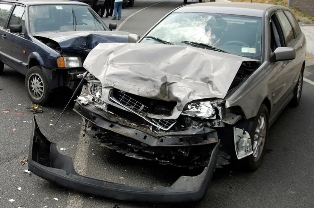 Front view of two crashed cars on the road with major damage to their front ends after an accident